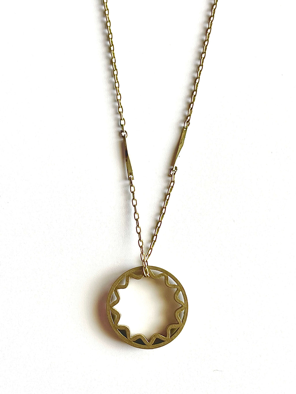 Yellow brass sun pendant on a yellow brass bar chain with a blue background