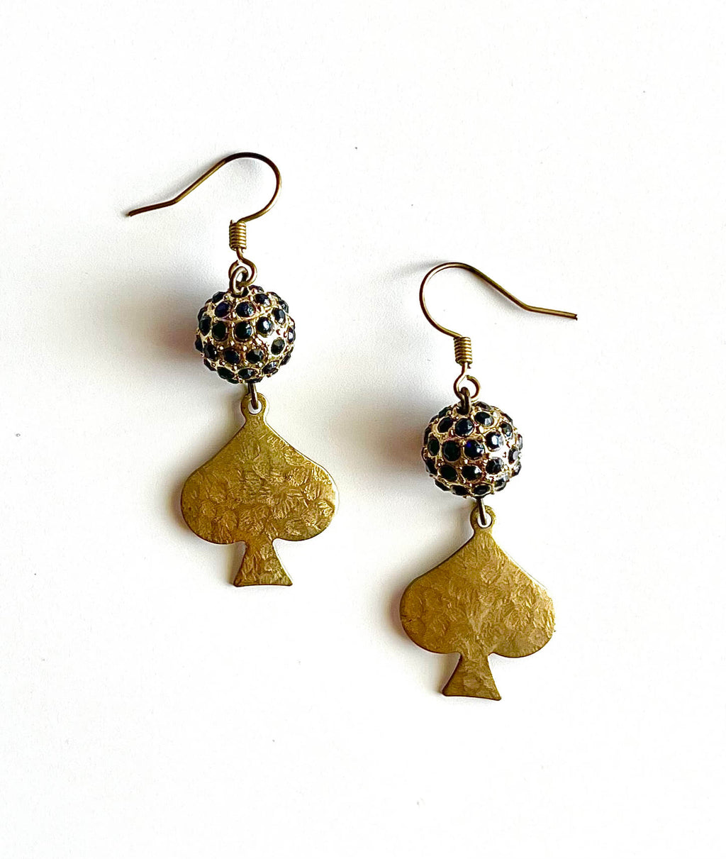 Yellow brass spade pendant earrings with black glass beads on a white background