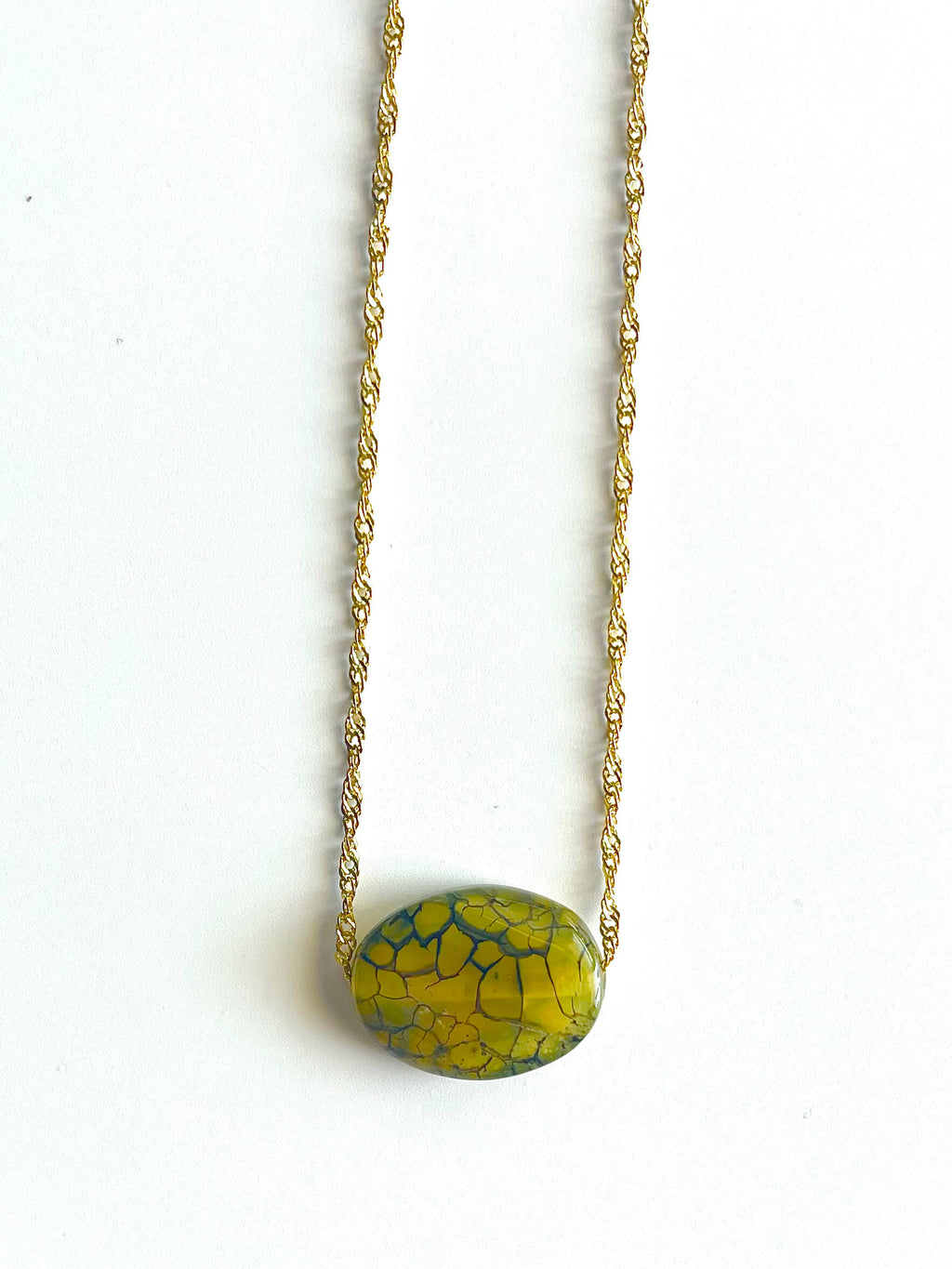 Necklace with a green and blue patterned pendant on a white background