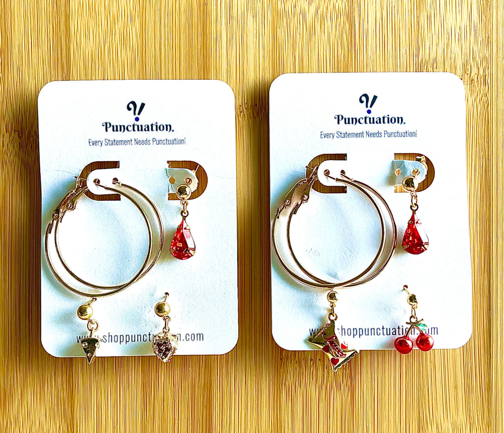 Pair of hoop earrings with red and black heart charms on Punctuation branded cards.