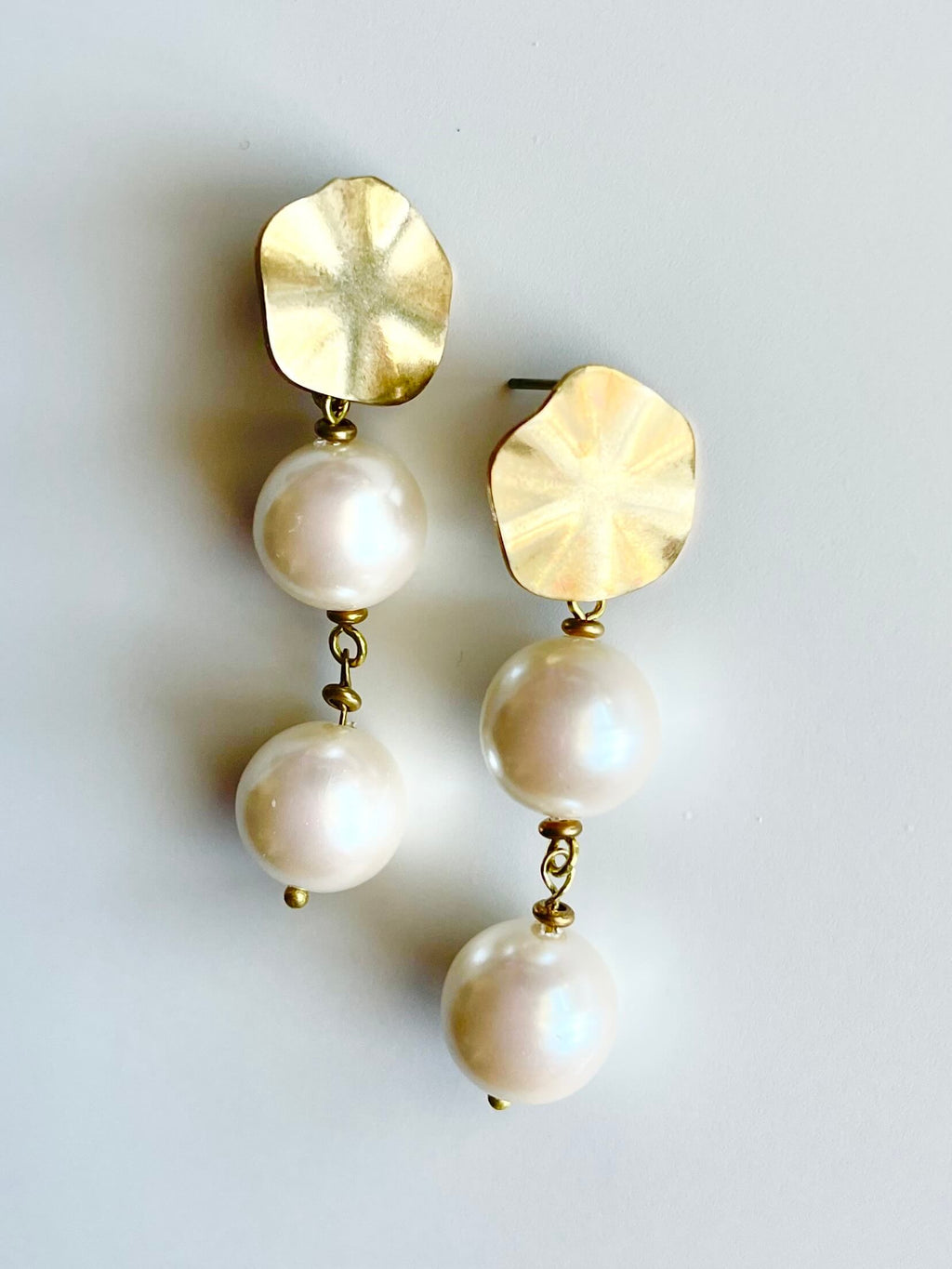 Gold and pearl earrings on a light gray background