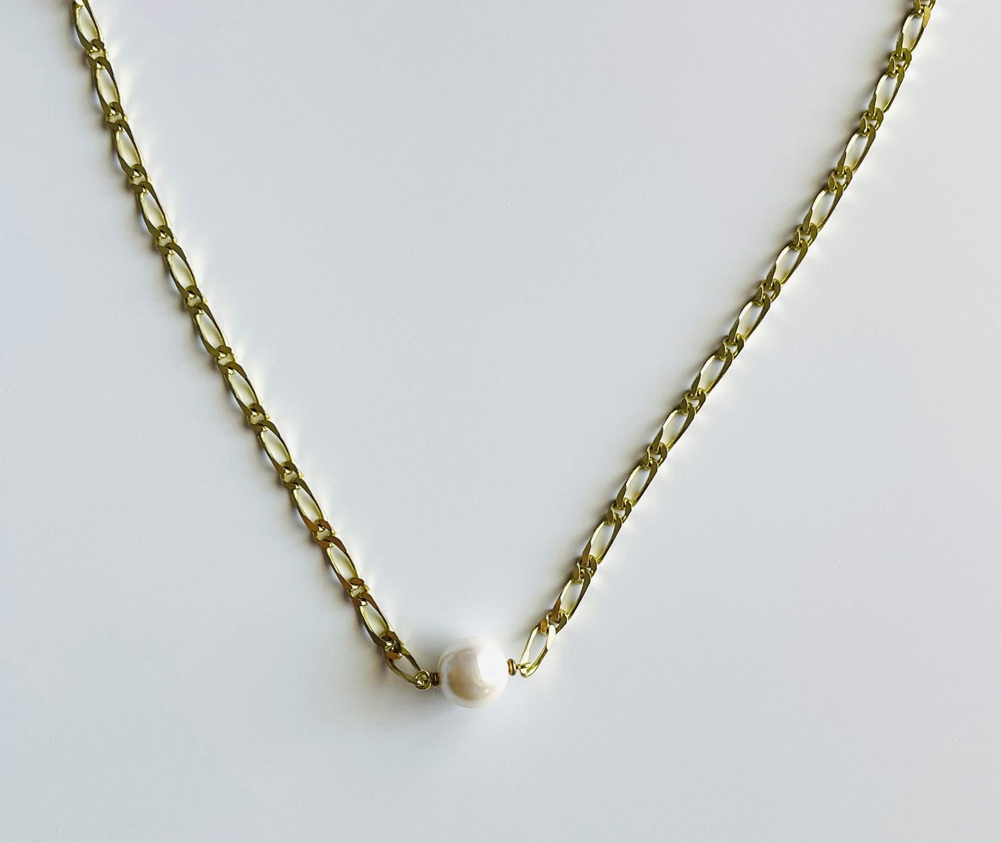 Yellow brass necklace with white glass pearl on white background