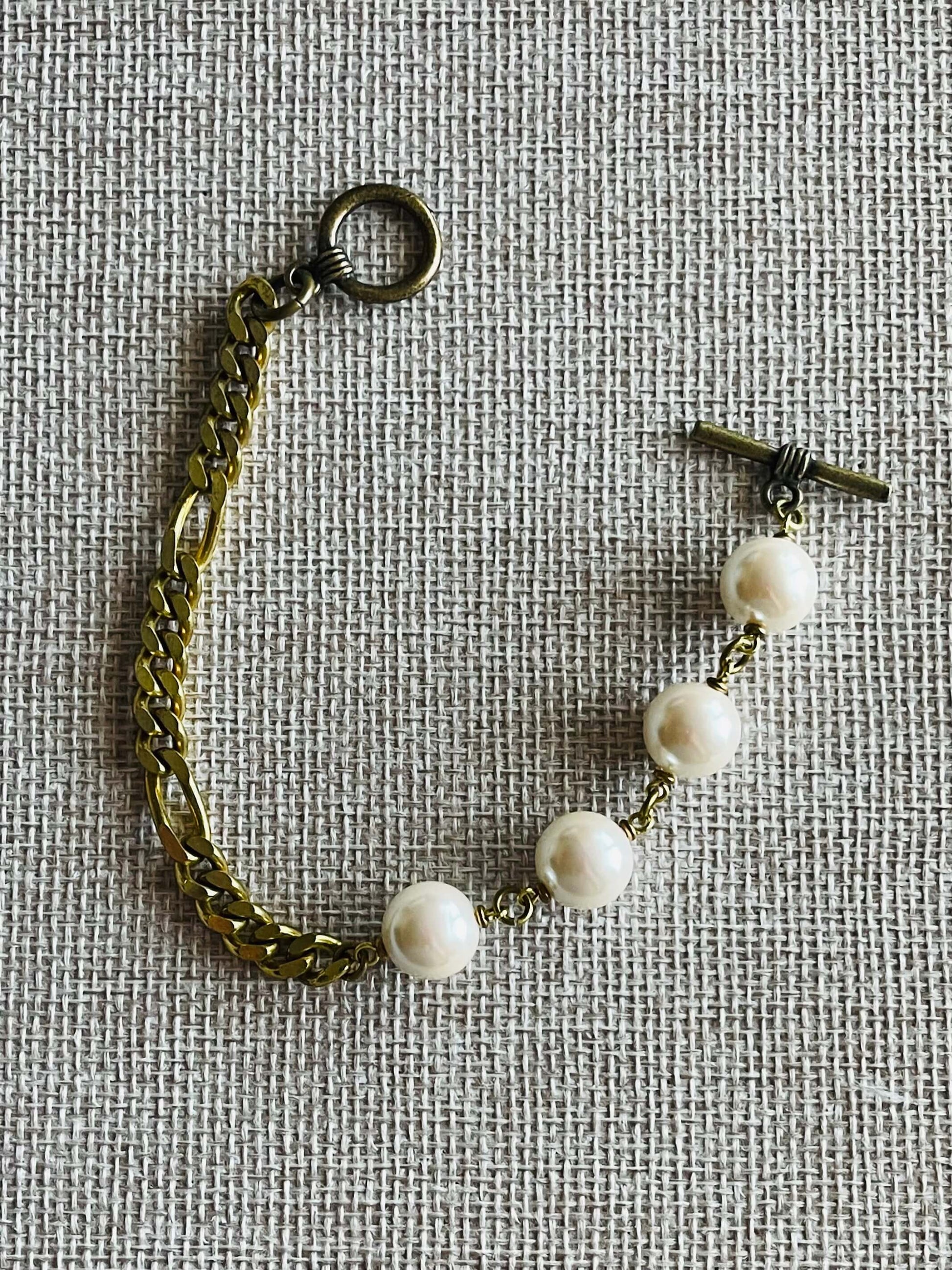Glass pearl strand with yellow brass chain bracelet on tan background
