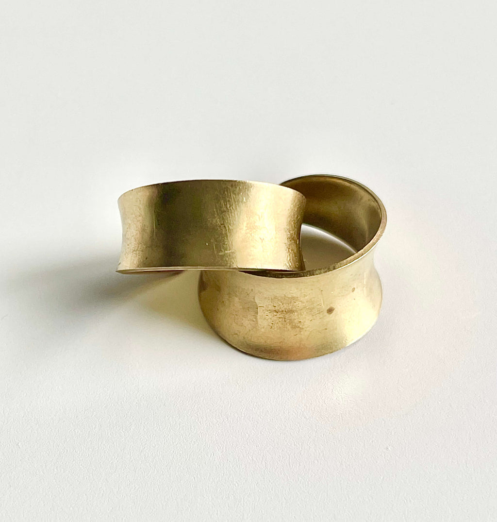Two brass adjustable rings stacked on top of one another on a white backdrop. 