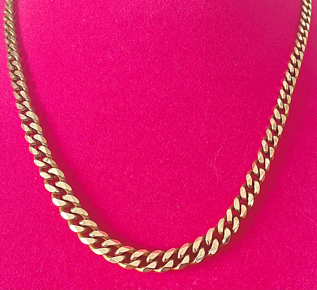 Yellow brass graduated curb chain necklace on a hot pink background