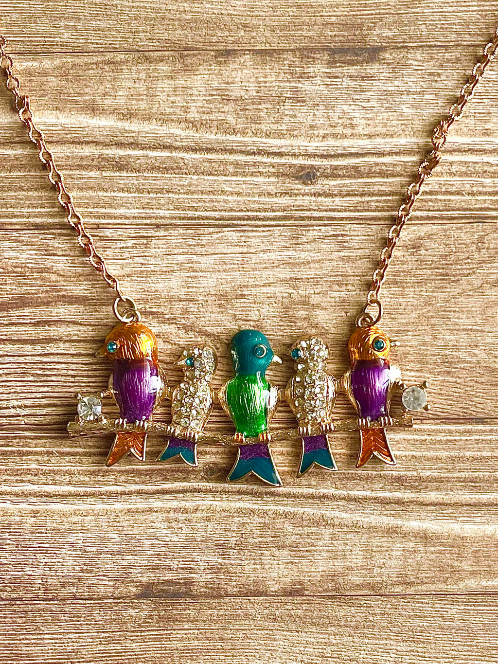 Necklace with colorful bird-shaped pendants on a wooden surface